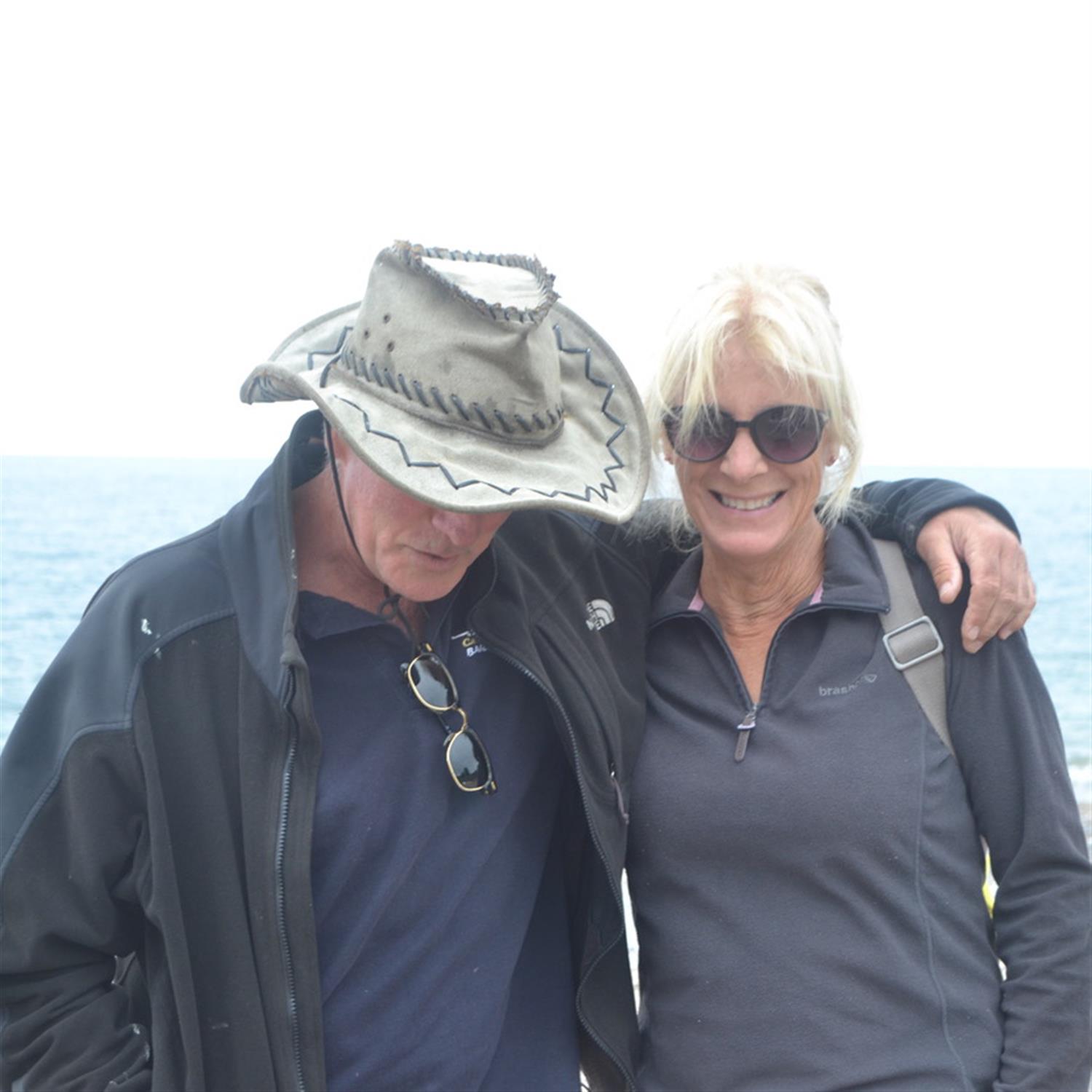 A man with a hat with his arm around a woman